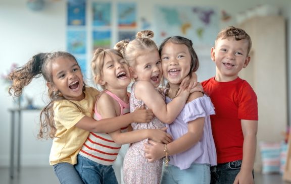 Smiling children of diverse backgrounds enjoying their time together, showcasing friendship and joy in a classroom environment. Highlights a multicultural group with vivid expressions sharing a joyful moment in education.